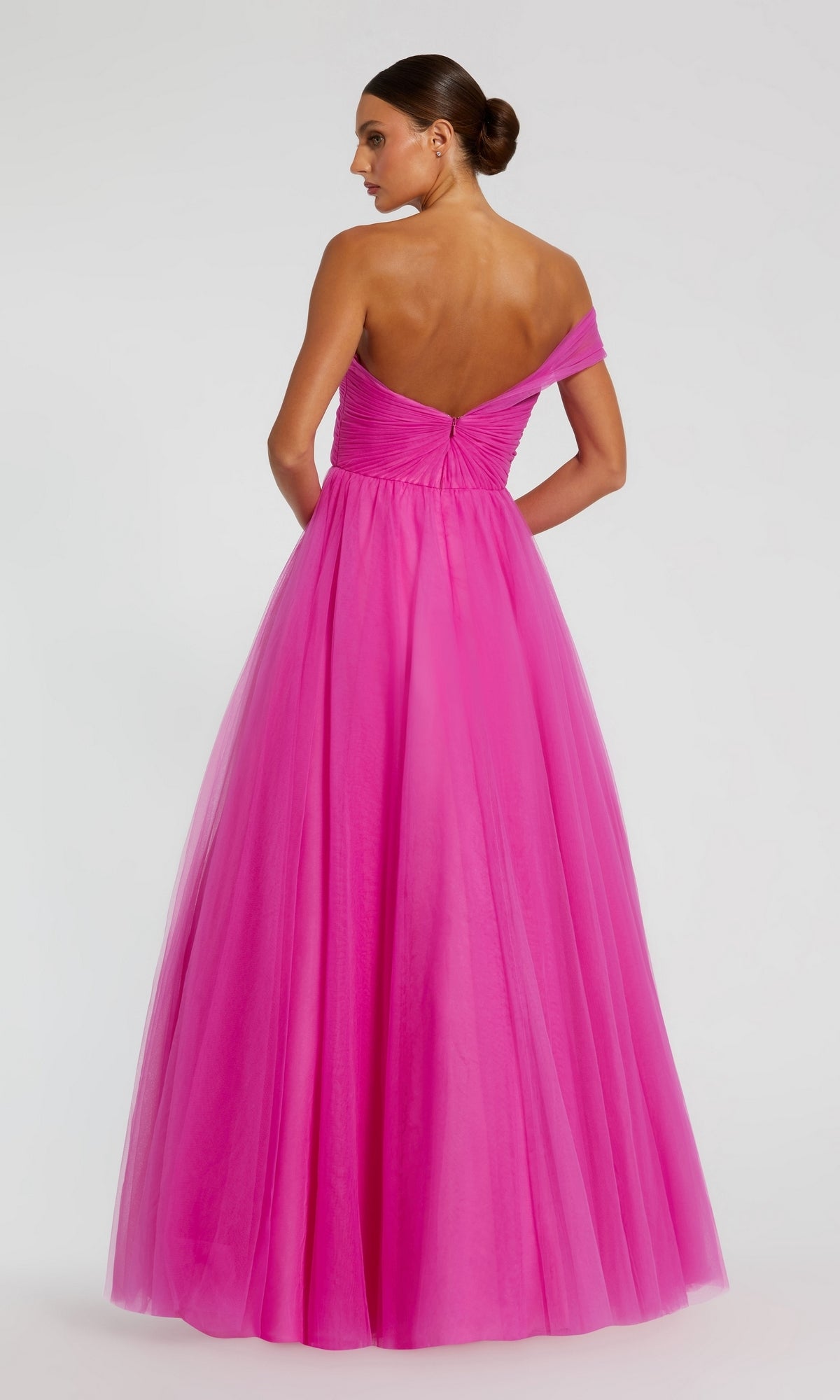 Woman facing away, wearing the Mac Duggal 68713 One-Strap Long Prom Ball Gown with a fitted bodice and full tulle skirt. Her hair is styled in a neat bun.