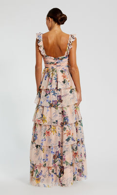 A woman faces away, wearing the Mac Duggal 68742 Long Formal Dress—a floor-length floral chiffon gown with ruffled straps, a ruched bustier bodice, and a tiered skirt elegantly cascading down her back.