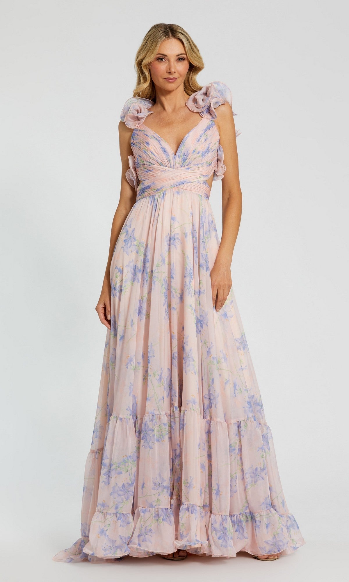 A woman wears the Mac Duggal 68753 Long Formal Dress in Violet Multi, featuring a tiered A-line silhouette with ruffled shoulder details, standing against a plain light background.