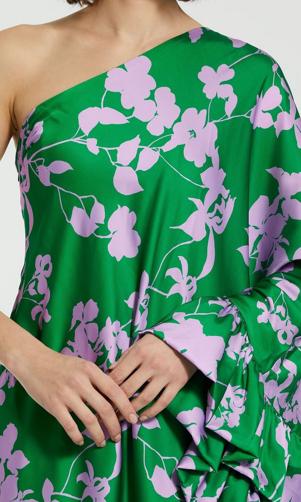 A person models the Mac Duggal 68787 Long Green Print Formal Dress, featuring a one-shoulder design and light purple floral pattern, shown from shoulders to mid-thigh against a plain background.