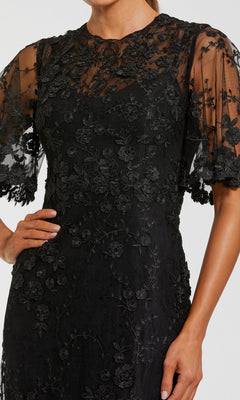 Model showcases the Flutter-Sleeve Long Formal Dress (Mac Duggal 68810), a black sheer lace dress with floral embroidery, displayed from shoulders to mid-thigh—a modern and elegant eveningwear option.