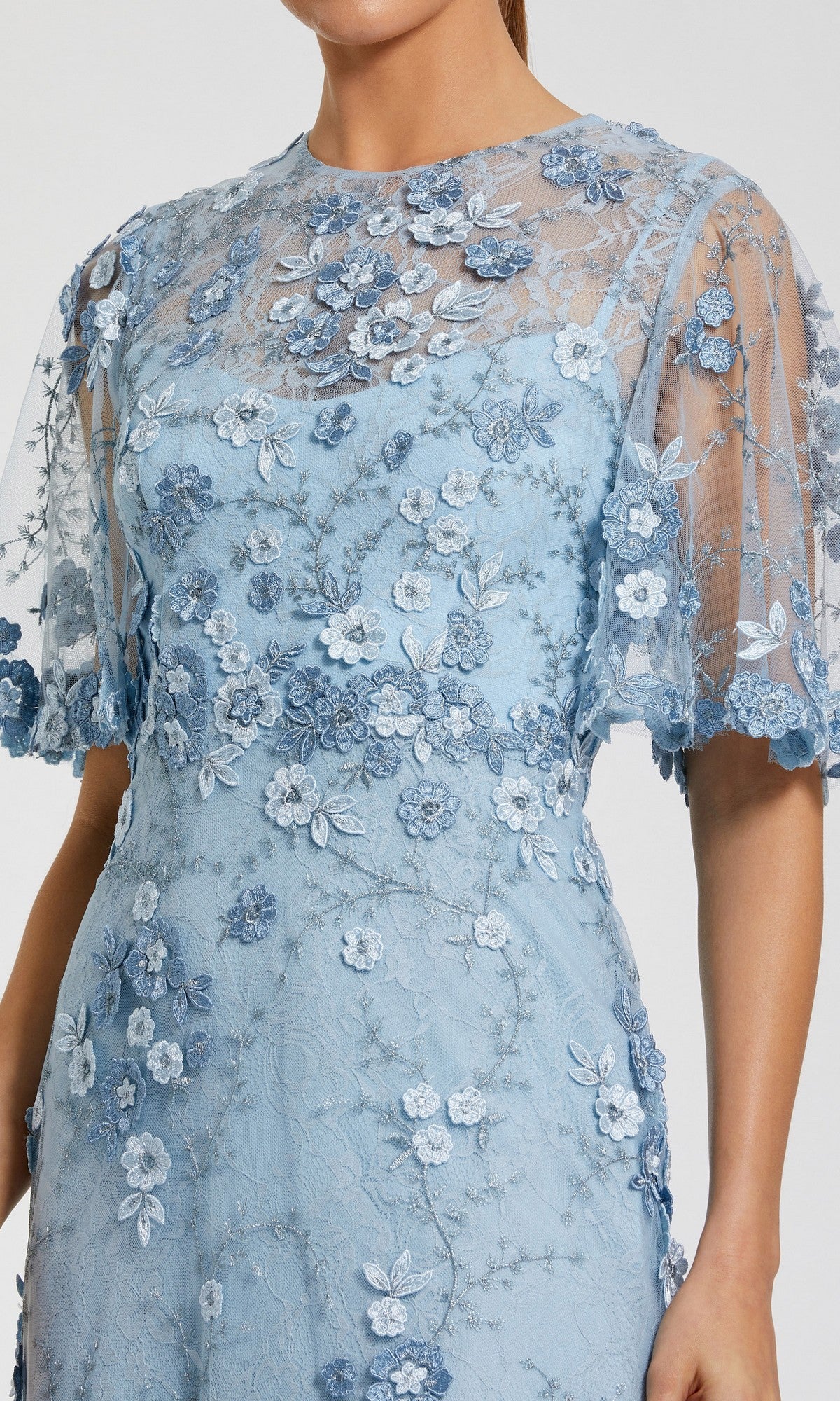 Model wearing the Mac Duggal 68810 Flutter-Sleeve Long Formal Dress in light blue, featuring short flutter sleeves, a sheer overlay, and floral embroidery; shown from shoulders to knees.