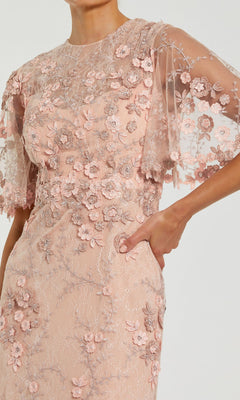 A model wears the Mac Duggal 68810 Flutter-Sleeve Long Formal Dress—a light pink gown with floral appliqué embroidery and sheer flutter sleeves, shown from neck to mid-thigh.