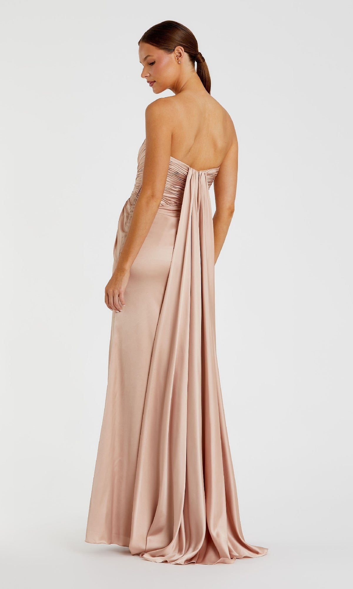 A woman models the Strapless Long Formal Dress: Mac Duggal 68837, a floor-length blush pink satin evening gown with a draped back detail, standing against a plain white background.