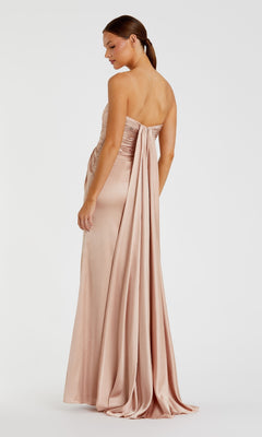 A woman models the Strapless Long Formal Dress: Mac Duggal 68837, a floor-length blush pink satin evening gown with a draped back detail, standing against a plain white background.