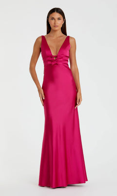 A woman stands against a white background wearing the Mac Duggal 68855 Raspberry Long Satin Prom Dress, featuring strappy back, floor-length silhouette, deep V-neckline, and lace-up front detail.