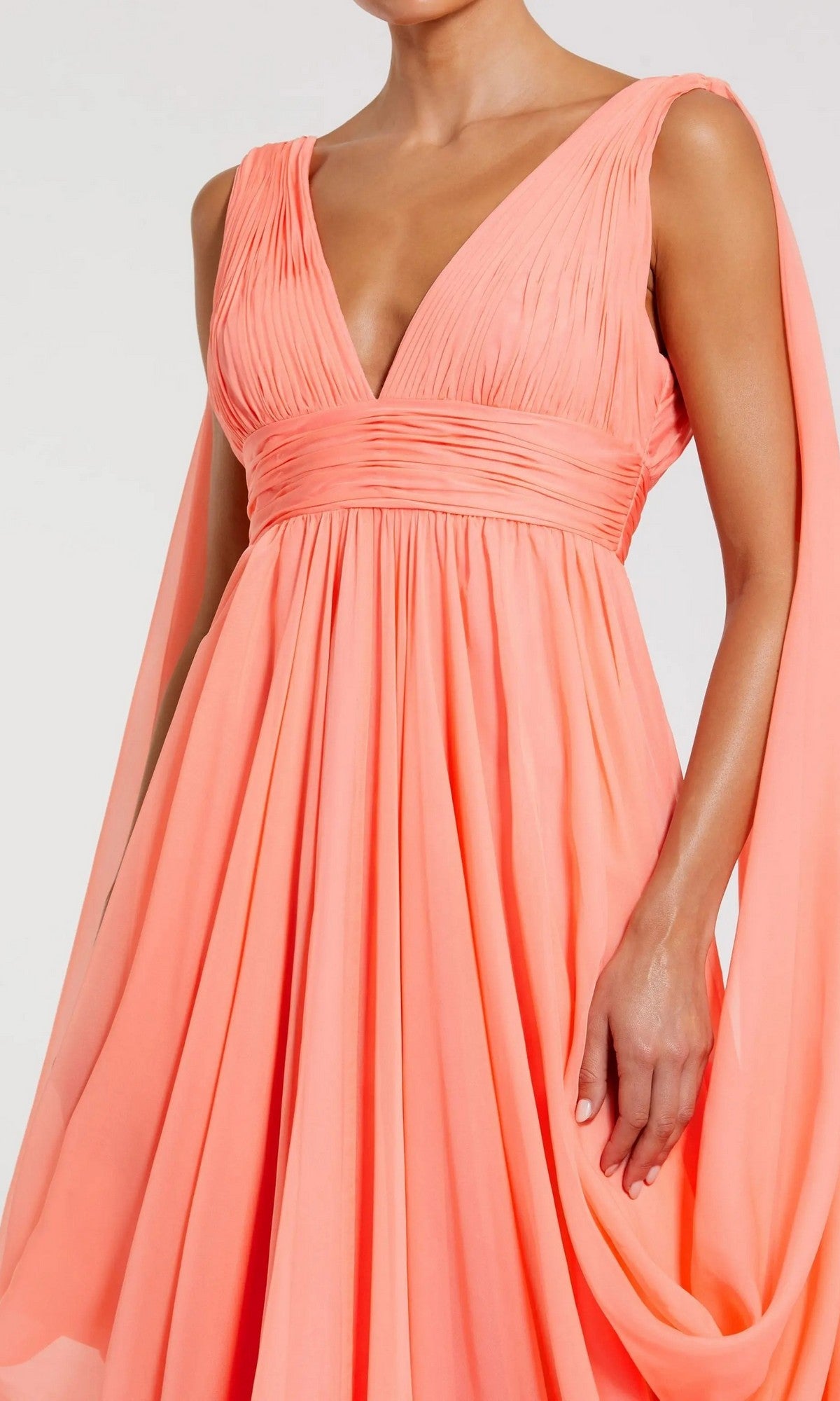 Model wearing the Mac Duggal 68860 long formal dress, a sleeveless coral-pink chiffon gown featuring a deep V-neck and graceful, flowing fabric detail, shown from shoulders to mid-thigh.