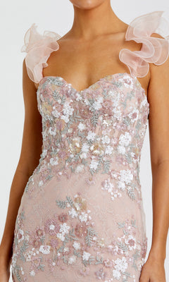 A person wearing the Mac Duggal 68880 Long Formal Dress, a sleeveless blush pink gown featuring floral embroidery, sequin details, bustier bodice, and ruffled straps.