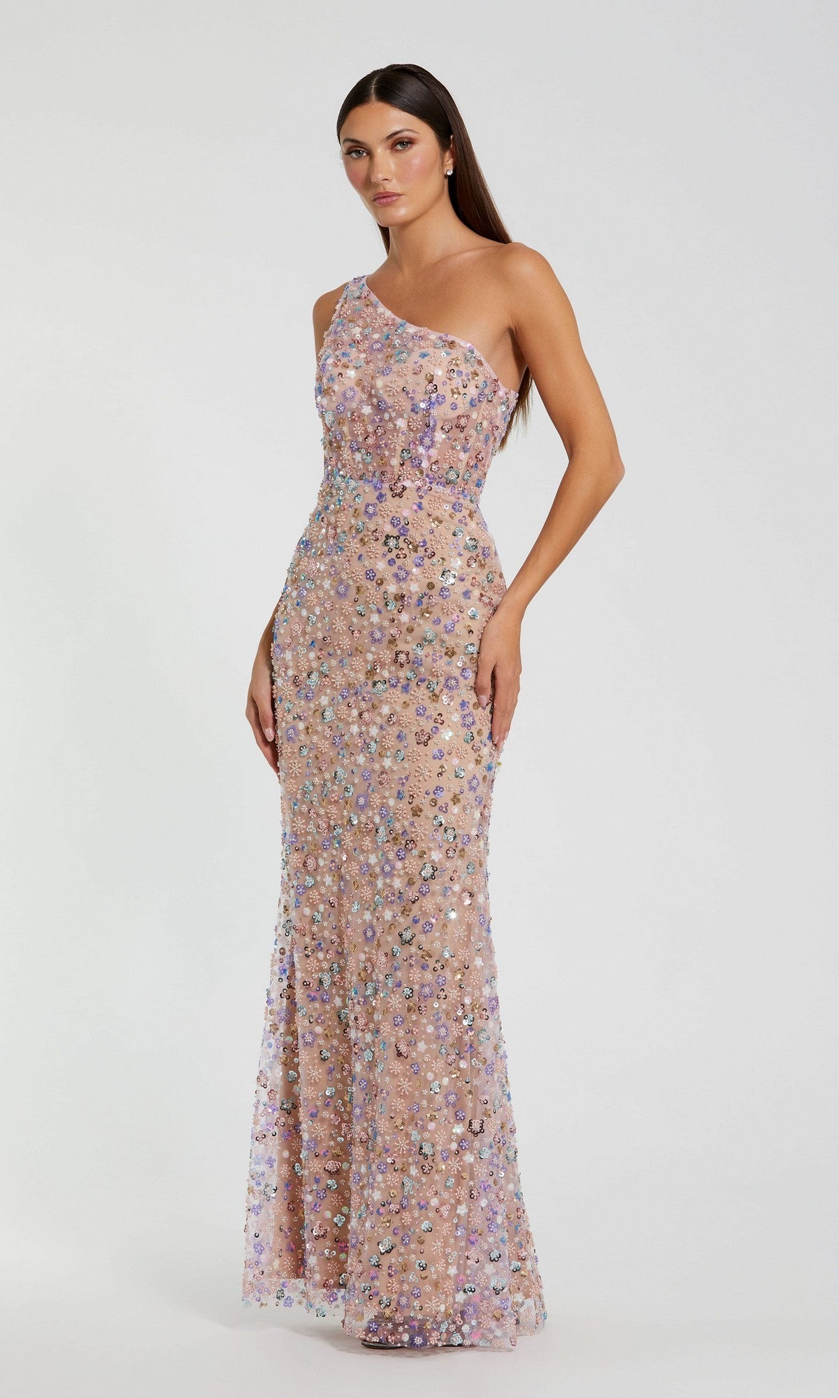 A woman wearing the Mac Duggal 68889 long prom dress in Pink Multi, featuring a floor-length, one-shoulder design with multicolored sequins, stands against a plain white background.