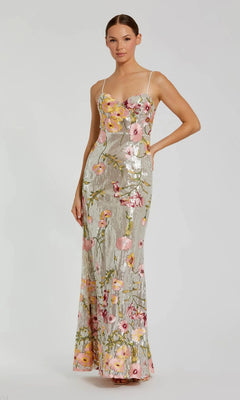 A woman wears the Mac Duggal 68896 long formal dress in Silver Multi, featuring silver sequins, pink floral embroidery, and thin straps, standing against a plain background.