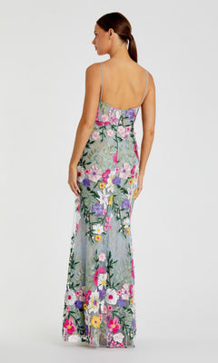 Woman facing away, wearing the Mac Duggal 68897 long formal dress—a sleeveless evening gown with colorful floral embroidery and thin straps—stands against a neutral background.