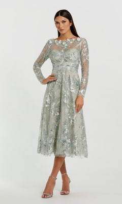 A woman wearing the Mac Duggal 68898 Midi Party Dress in Mist—a light blue, floral-embroidered dress featuring delicate lace and long sleeves—paired with silver strappy heels, standing against a plain white background.