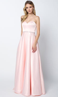 A woman stands against a plain background wearing the Juliet 688 Long Prom Dress—a floor-length, light pink satin gown with a strapless, fitted bodice, subtle waistband embellishment, and a gentle sweetheart neckline.