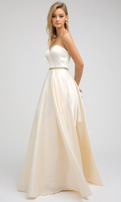 A woman models the Juliet 688 long prom dress—an ivory, strapless A-line gown featuring a sweetheart neckline, beaded waistline, elegant fitted bodice, and floor-length skirt—set against a plain light background.