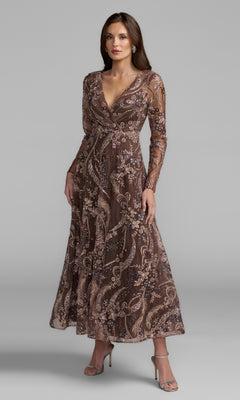 A woman wearing the Mac Duggal 68906 Champagne Midi Party Dress in chocolate—a long-sleeve, V-neck design featuring intricate floral and paisley patterns—stands in neutral high heels against a plain gray background.