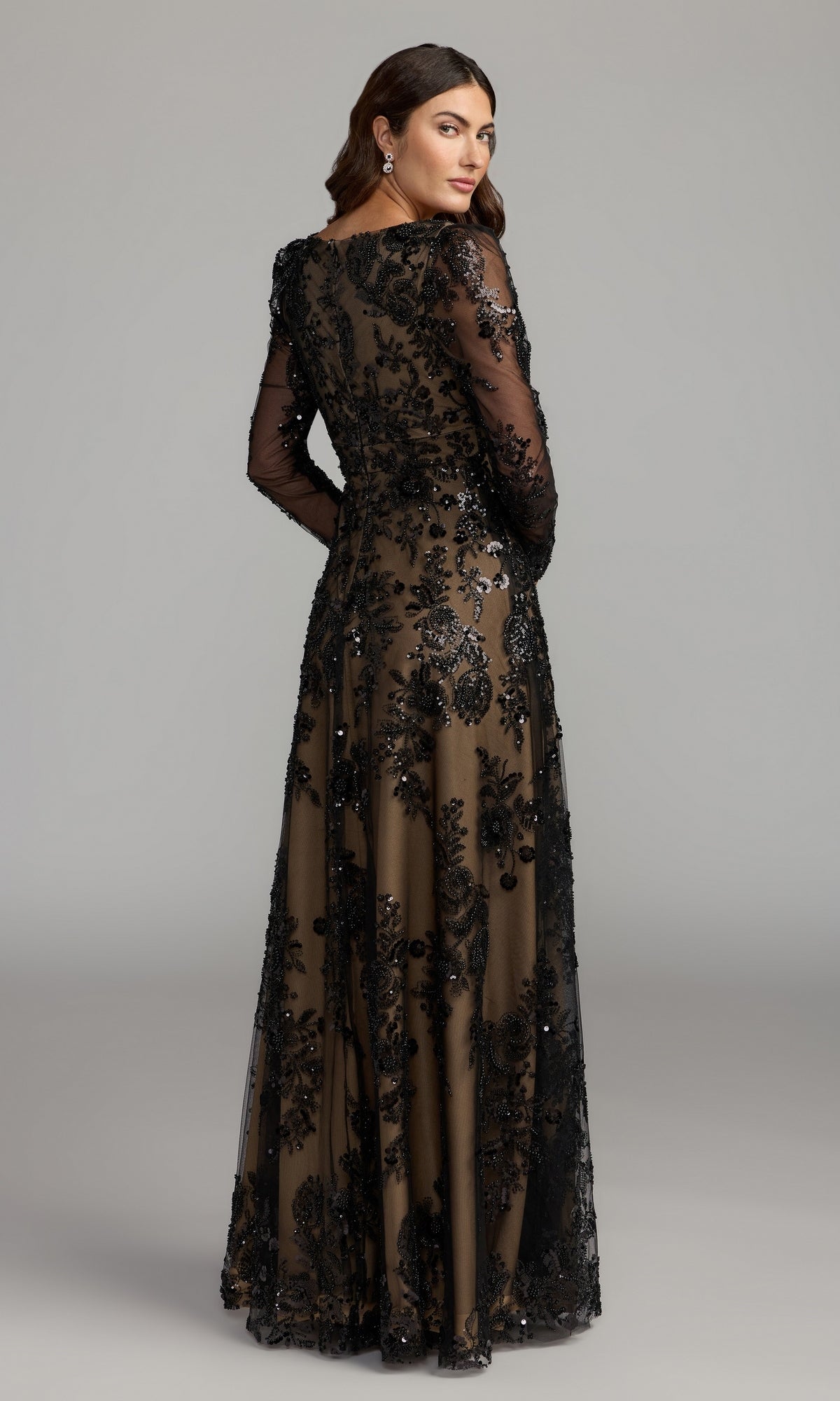 Woman in the Mac Duggal 68908 long sleeve long formal dress, featuring a floor-length silhouette with black lace embroidery and delicate floral detailing, shown from the back against a plain gray background—an elegant option for a formal gown or mother of the bride dress.
