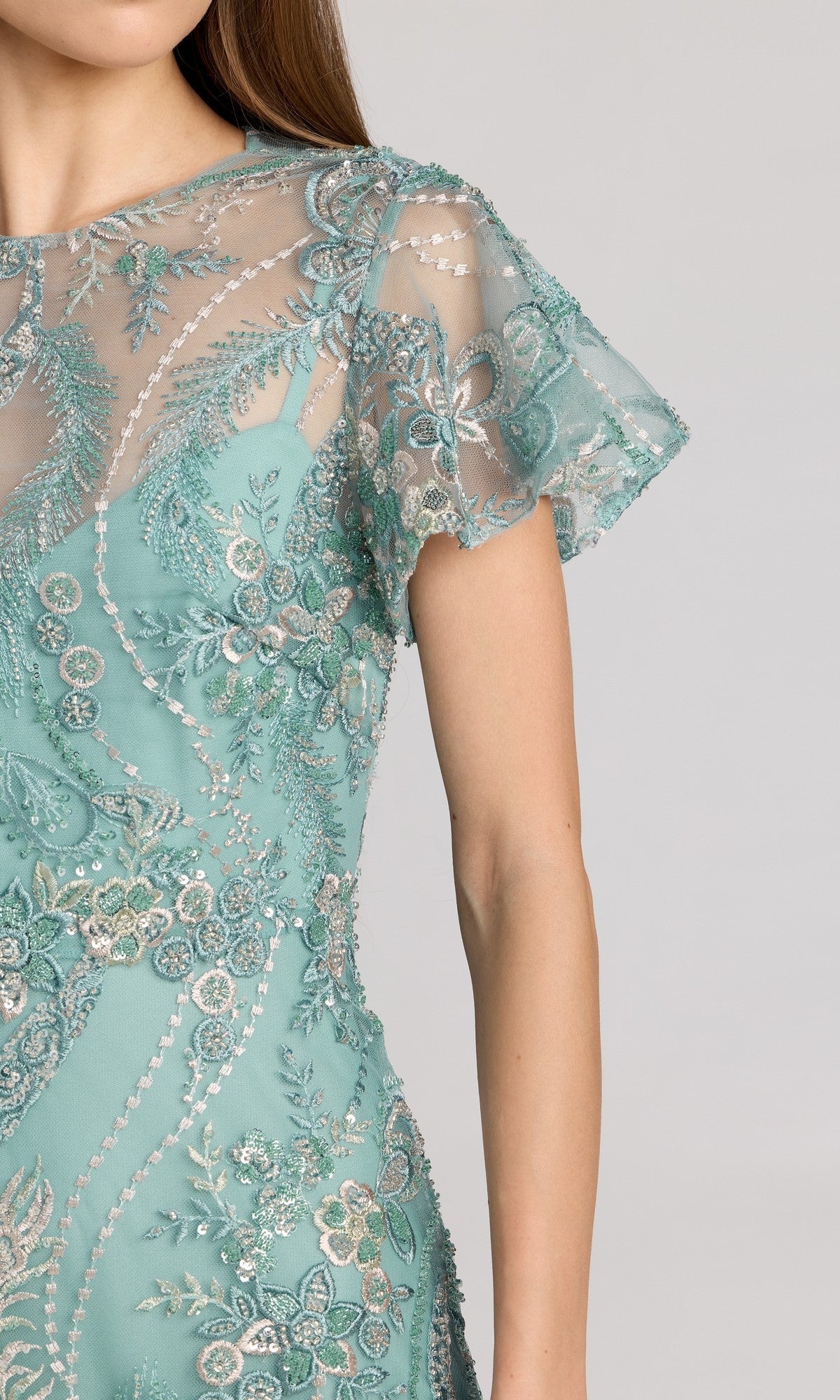 A woman wearing the Mac Duggal 68909 tea-length party dress in light blue-green, adorned with silver and floral beaded embroidery, featuring a sheer mesh top and short sleeves.