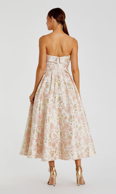 A woman faces away, wearing the Mac Duggal 68928 long formal dress with a fitted bodice and flared skirt, paired with gold high heels.