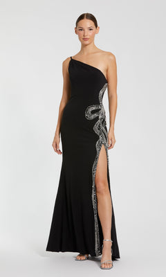 A woman in the Mac Duggal 68932 long formal dress—black, one-shoulder, with silver embellishments and a thigh-high slit—stands against a plain background, embodying timeless elegance.