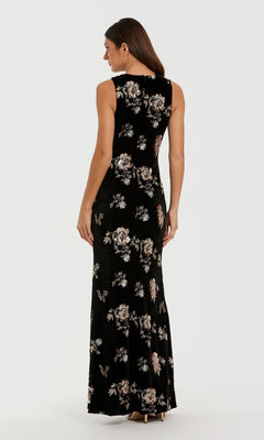 A woman stands facing away, wearing the Mac Duggal 68959 Black Velvet Print Formal Dress with neutral high heels against a plain white background.