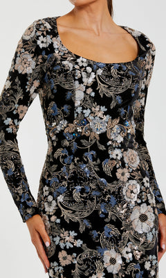 A woman in the Black Velvet Print Formal Gown (Mac Duggal 68978), featuring intricate blue, white, and beige embroidered sequin floral designs.