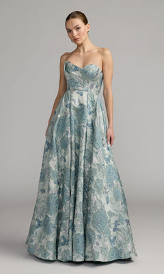 A woman wearing the Long Formal Dress: Mac Duggal 68999—a strapless, floor-length brocade ballgown in seafoam with a delicate floral pattern—stands against a plain gray background.