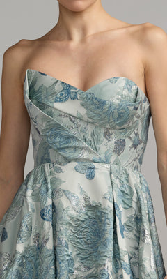 A woman wearing the Mac Duggal 68999 long formal dress, featuring a strapless, sweetheart neckline and a blue and silver floral pattern. Only her upper body is visible.