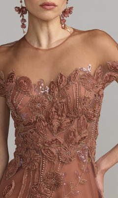 A woman is shown from shoulders to waist wearing a sheer, rose-colored dress adorned with intricate floral embroidery and matching floral earrings—a striking contrast to the classic Mac Duggal 69003 Cap-Sleeve Black Formal Dress featuring elegant beaded lace.