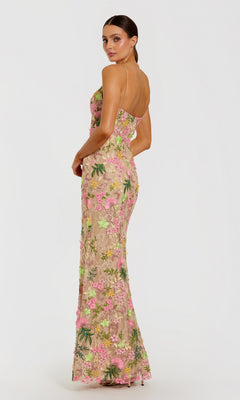 A woman stands against a plain white background, looking over her shoulder while wearing the Mac Duggal 69010 long formal dress. This elegant gown features a fitted, sleeveless silhouette adorned with pink, yellow, and green floral embroidery.