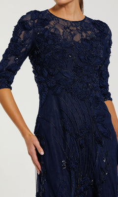 A woman wearing the Mac Duggal 69016 Long Sleeve Beaded Formal Gown, a navy blue dress with floral embroidery and bead detailing—ideal for the mother of the bride.