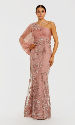A woman stands against a plain white background wearing the Mac Duggal 69019 long formal dress in mocha—a floor-length, one-shoulder gown featuring a sheer long sleeve and silver floral embroidery.