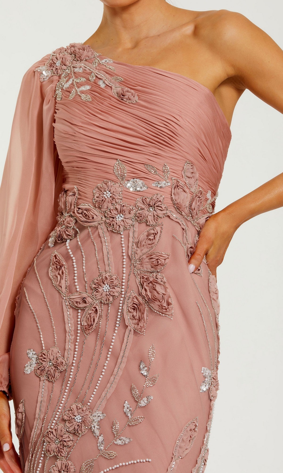 Person wearing the Mac Duggal 69019 long formal dress in mauve, featuring a one-shoulder design with a sheer sleeve, floral appliqué, and silver sequin details.