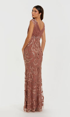 A woman stands against a plain light background, looking over her shoulder in the Mac Duggal 69022—a mauve, floor-length formal dress with beaded floral appliqué, sequins, and lace detailing.