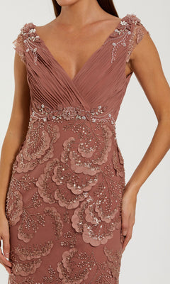 A woman in the Mac Duggal 69022 long formal dress, featuring a sleeveless rose hue with beaded floral appliqué and intricate embroidery, shown from shoulder to thigh.