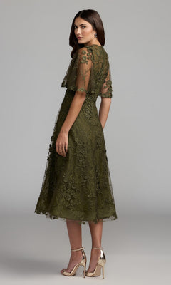 Woman wearing the Lace Midi Wedding Guest Dress: Mac Duggal 69036—a knee-length, olive green short sleeve lace midi dress—paired with metallic high-heeled sandals and standing against a plain gray background; a chic choice for any wedding guest.