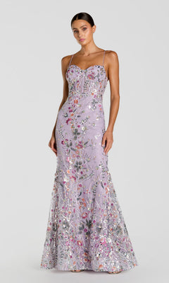 A woman wearing the Mac Duggal 69049 long formal dress in Lilac Multi, featuring a fitted silhouette with thin straps and floral sequin embroidery, stands against a plain light gray background.