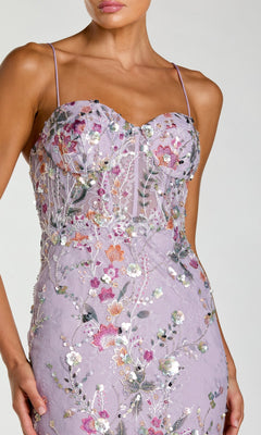 A woman wearing the Mac Duggal 69049 long formal dress in lilac, featuring thin straps and floral embroidered details, shown from shoulders to mid-thigh against a plain background.