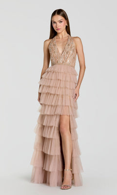 A woman wears the Mac Duggal 69062 Long Formal Dress—a sleeveless nude sequined halter gown featuring a tiered tulle skirt and high slit—while standing against a plain light background.