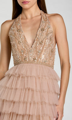 A woman is wearing the Mac Duggal 69062 long formal dress in blush pink, showcasing a sleeveless deep V-neck design with a beaded and sequined bodice, complemented by a layered tulle skirt—an elegant and sophisticated choice for any formal occasion.