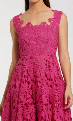A woman wearing the Midi Party Dress: Mac Duggal 69073—this sleeveless, bright pink dress features intricate floral lace patterns, a fitted bodice, and an elegant A-line midi silhouette.