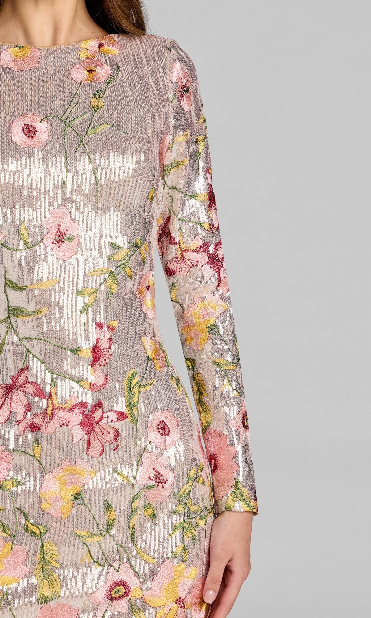 A close-up of a woman’s upper body wearing the Mac Duggal 69075 Short Party Dress, featuring long sleeves and vibrant pink, yellow, and green floral embroidery on shiny, textured fabric—perfect for making a statement as a sequin floral dress at your next event.