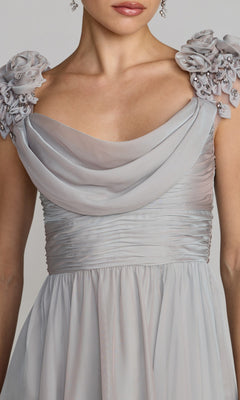 A woman wearing the Mac Duggal 69088 long formal dress in light gray, featuring a ruched chiffon design, draped neckline, and embellished floral shoulder details.