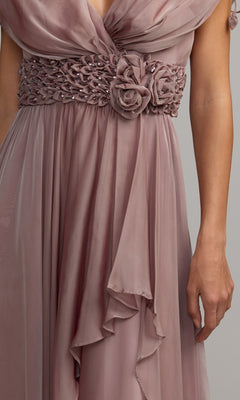 A close-up of the Long Formal Dress: Mac Duggal 69089 in mauve chiffon, showcasing its ruched bodice, crystal-embellished waistband with delicate floral detailing, and sheer flowing fabric, worn by a person with one arm visible.