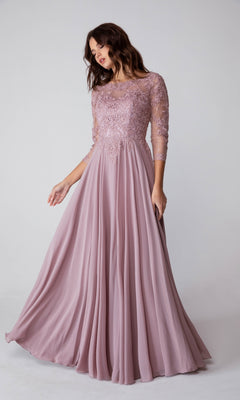 A woman in the Eureka 6909 Long-Sleeve Long Formal Dress, featuring a lace bodice and flowing mauve A-line skirt, stands against a plain light background.