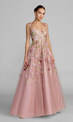 A woman wearing the Long Formal Dress: Mac Duggal 69143, a sleeveless, floor-length gown in Mocha, featuring delicate floral embroidery, stands against a plain gray background.