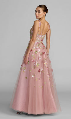 A woman in the Mac Duggal 69143 Long Formal Dress, an elegant pink A-line gown with delicate floral embroidery and thin straps, stands facing slightly away while looking over her shoulder.