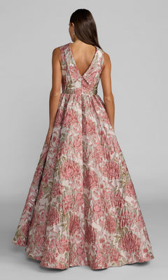 A woman is seen from behind wearing the Mac Duggal 69177 long formal dress, a sleeveless, floor-length ballgown crafted from pink floral brocade with a deep V-back. The gown features a stunning blend of pink, green, and beige patterned fabric.
