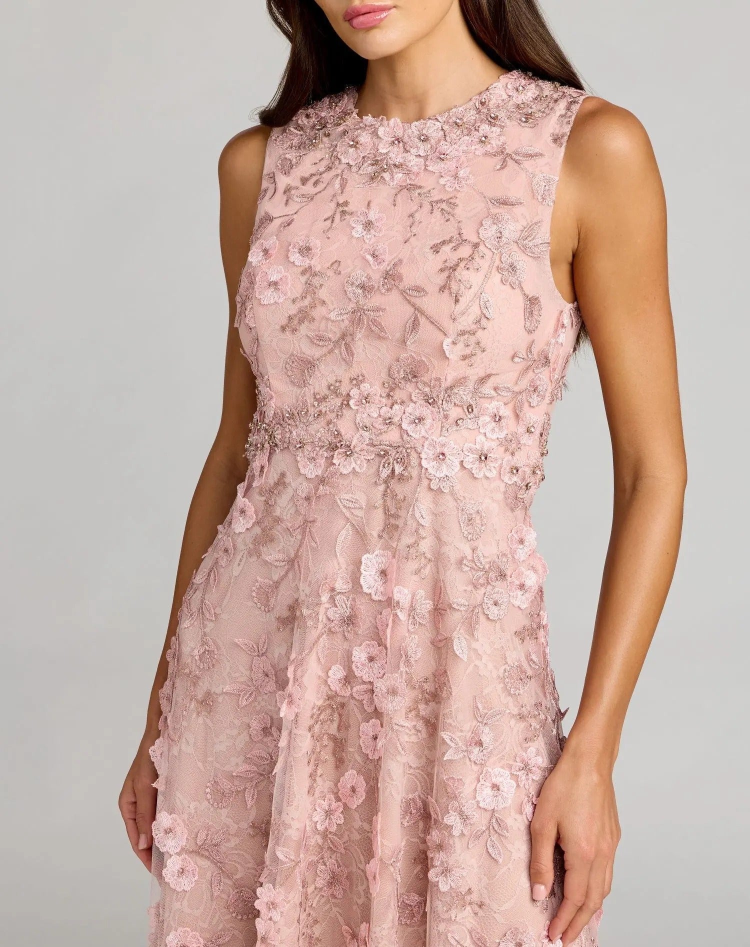 A woman wearing the Mac Duggal 69192 Tea-Length Party Dress—an elegant, sleeveless light pink lace party dress with a fitted bodice, A-line skirt, and 3D floral details—stands against a neutral background.