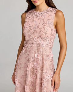 A woman wearing the Mac Duggal 69192 Tea-Length Party Dress—an elegant, sleeveless light pink lace party dress with a fitted bodice, A-line skirt, and 3D floral details—stands against a neutral background.