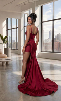 A woman wearing the Long Prom Dress: Atria 6926H, featuring a sexy high leg slit and v-neckline, poses indoors by large windows with city buildings visible outside and modern furniture in the background.